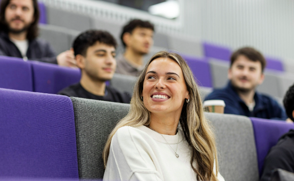 student sitting in lecture theatre surrounded by other students 